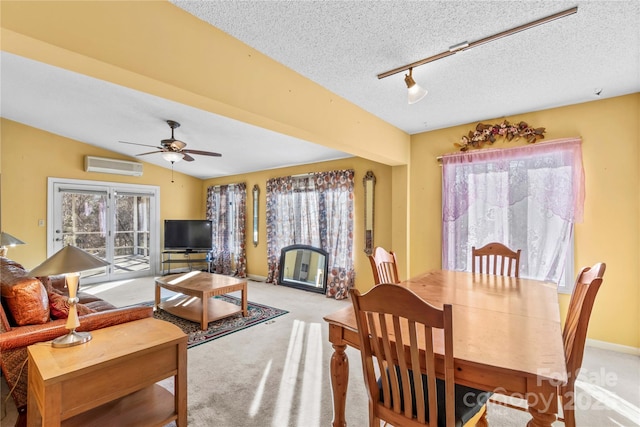 carpeted dining area with vaulted ceiling, a wall unit AC, a textured ceiling, and plenty of natural light