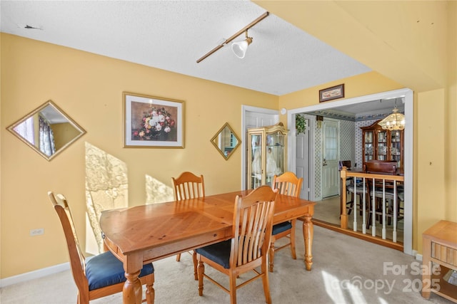 carpeted dining room with a textured ceiling