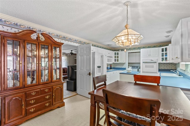 dining room featuring sink, ornamental molding, a textured ceiling, and ceiling fan