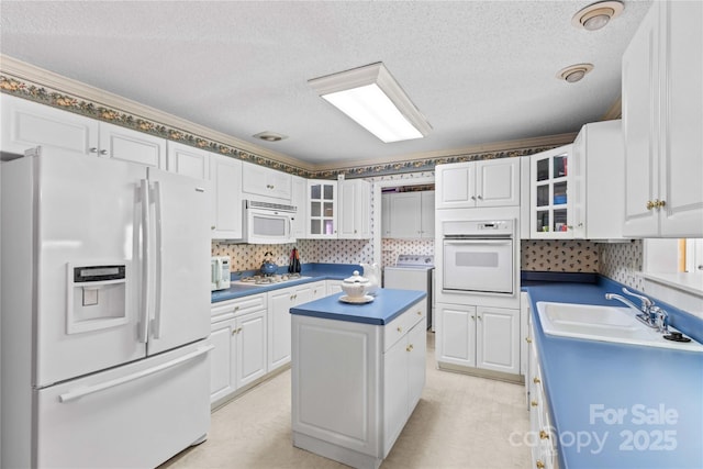 kitchen featuring white appliances, washer / dryer, sink, and white cabinets