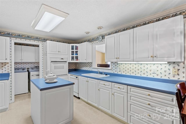 kitchen with sink, white cabinets, washer and clothes dryer, a center island, and white appliances