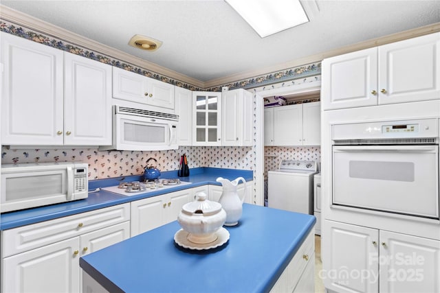 kitchen featuring white cabinetry, white appliances, and washer / dryer