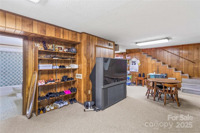 kitchen featuring carpet floors, a textured ceiling, and wooden walls