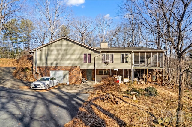 back of property featuring a garage and a sunroom