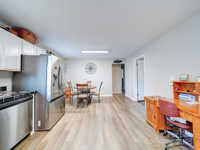 kitchen featuring stainless steel appliances, white cabinets, and light wood-type flooring