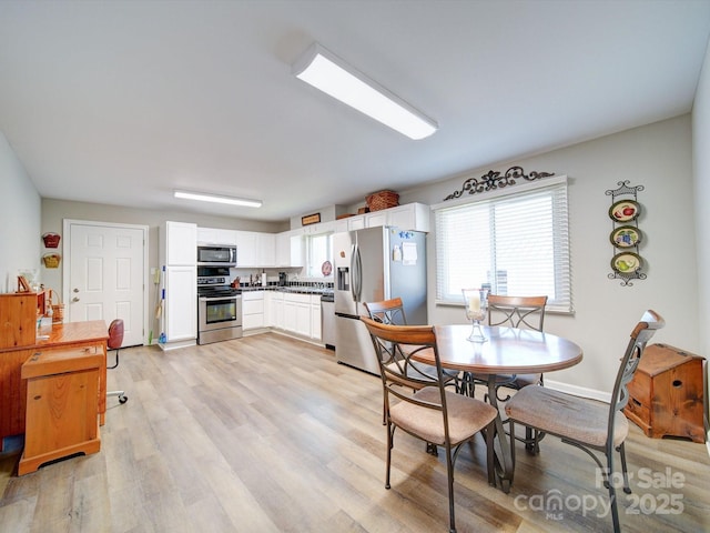 kitchen with light hardwood / wood-style flooring, white cabinets, and appliances with stainless steel finishes