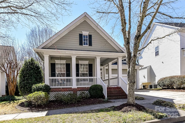 view of front of house featuring driveway, covered porch, and central air condition unit