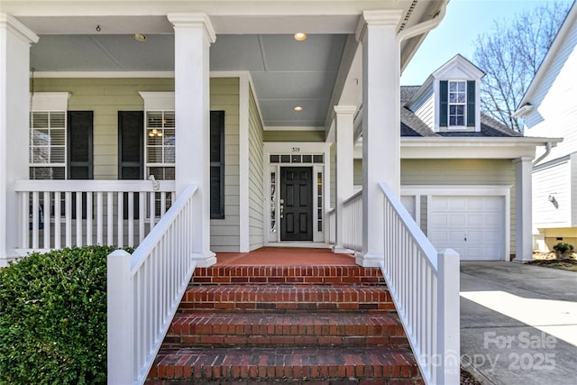 doorway to property with driveway, a shingled roof, a porch, and an attached garage