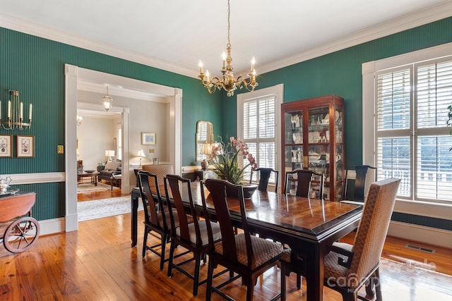 dining area featuring ornamental molding, wood-type flooring, and a notable chandelier