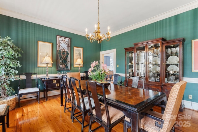 dining room with crown molding, a notable chandelier, and light wood-type flooring