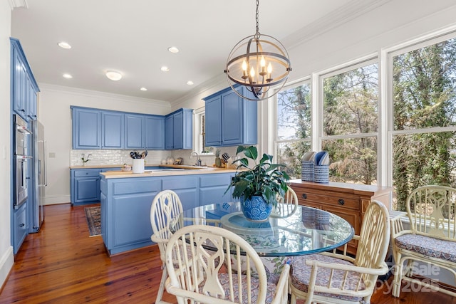 kitchen featuring tasteful backsplash, ornamental molding, blue cabinets, and dark hardwood / wood-style floors