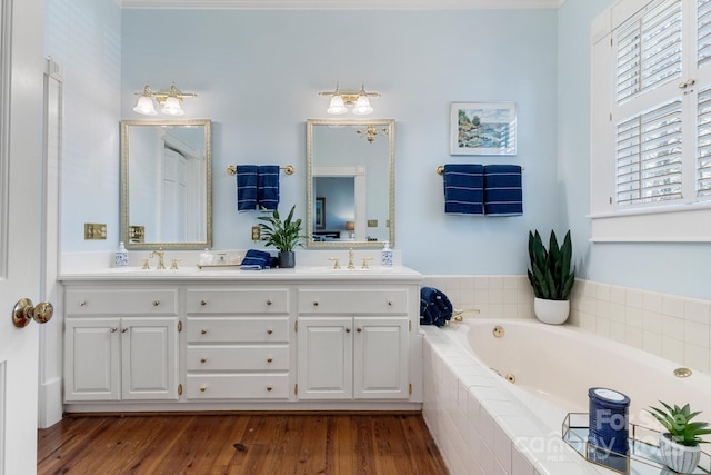 bathroom featuring a relaxing tiled tub, vanity, and wood-type flooring