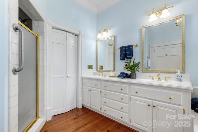 bathroom with vanity, crown molding, wood-type flooring, and a shower with door