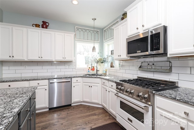 kitchen with appliances with stainless steel finishes, pendant lighting, sink, white cabinets, and dark stone counters