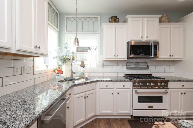 kitchen featuring sink, dark wood-type flooring, appliances with stainless steel finishes, white cabinets, and decorative light fixtures