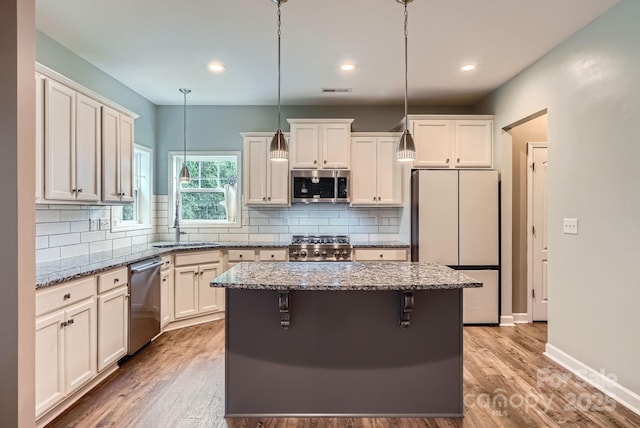 2864 Park Ridge Blvd, Rock Hill, SC 29732 - kitchen featuring stainless steel appliances, a center island, light stone countertops, light wood-style floors, and decorative light fixtures