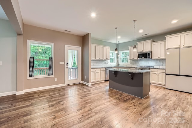 2864 Park Ridge Blvd, Rock Hill, SC 29732 - kitchen featuring stainless steel appliances, a center island, light wood-style floors, decorative backsplash, and light stone counters