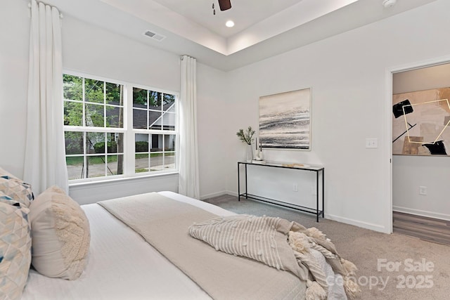 carpeted bedroom featuring a tray ceiling and ceiling fan