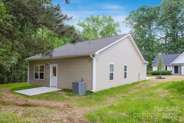 rear view of property featuring a yard, central AC, and a patio area