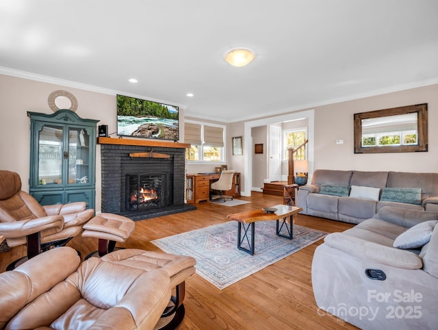 living room featuring crown molding, a brick fireplace, and light wood-type flooring