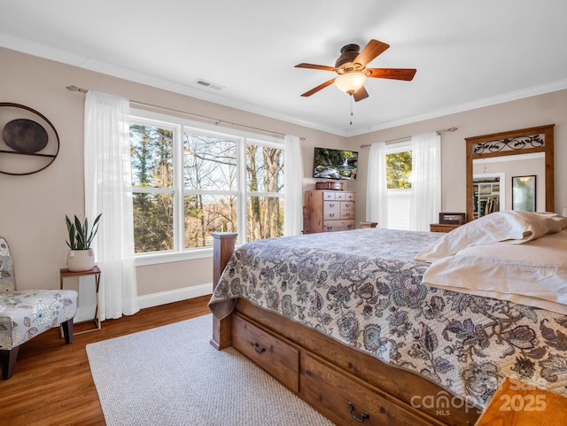 bedroom with hardwood / wood-style floors, ornamental molding, and ceiling fan