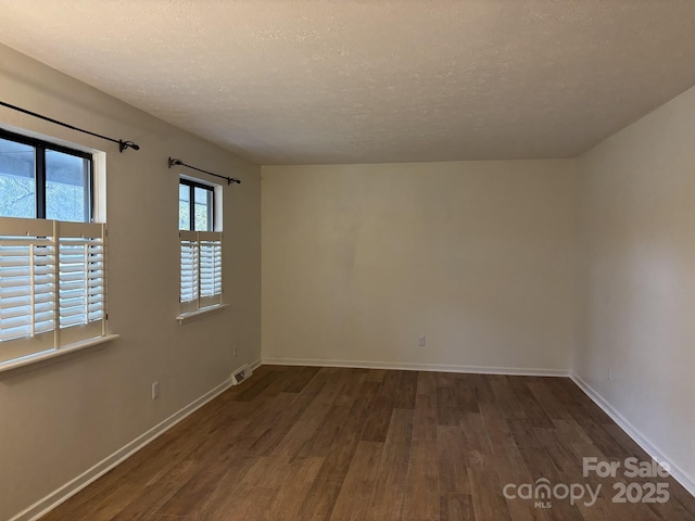 empty room with dark wood-type flooring and a textured ceiling