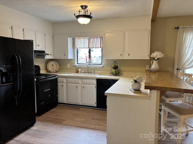 kitchen featuring sink, black appliances, kitchen peninsula, and white cabinets