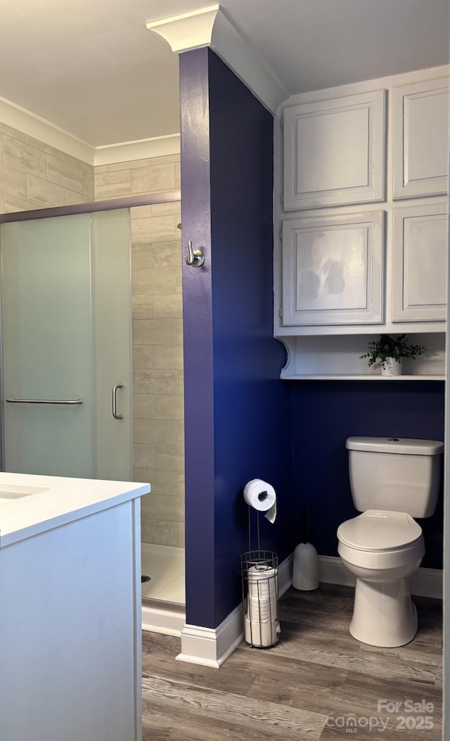 bathroom featuring a shower with door, vanity, hardwood / wood-style flooring, and toilet