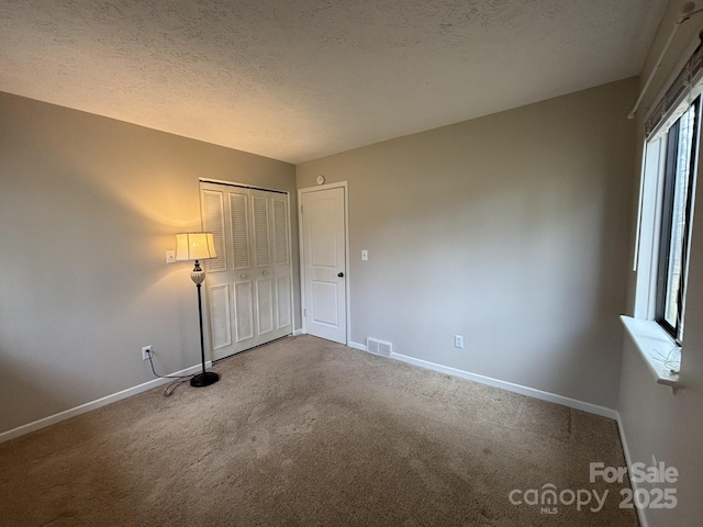 unfurnished bedroom featuring a closet, a textured ceiling, and carpet