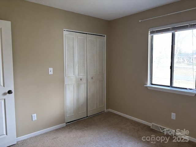 unfurnished bedroom with light carpet and a closet