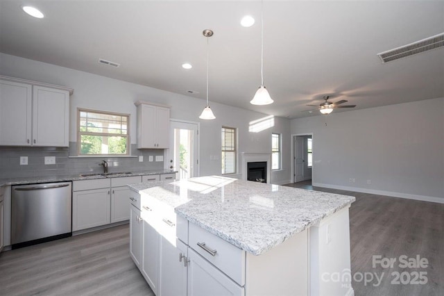 kitchen with sink, dishwasher, white cabinetry, a kitchen island, and decorative backsplash