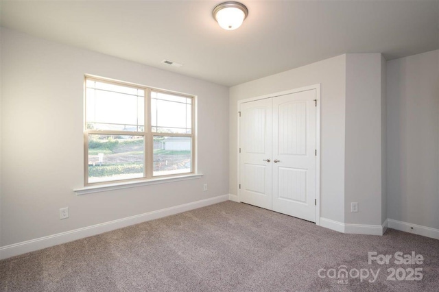 unfurnished bedroom with light carpet and a closet