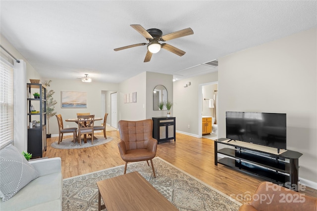 living room featuring hardwood / wood-style flooring, ceiling fan, and a textured ceiling