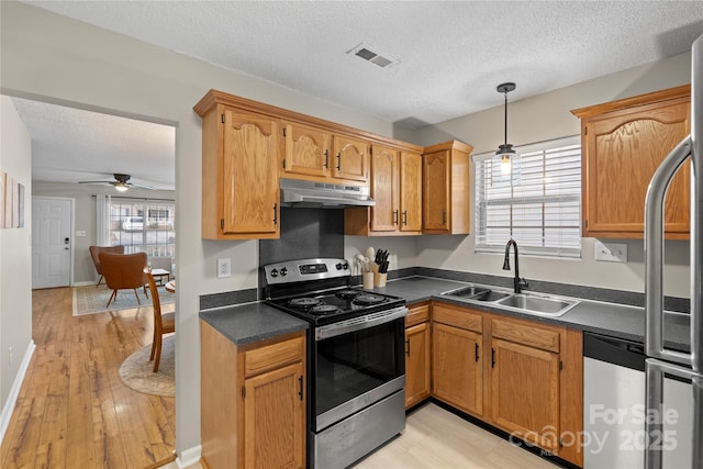 kitchen with sink, hanging light fixtures, stainless steel appliances, a textured ceiling, and light wood-type flooring