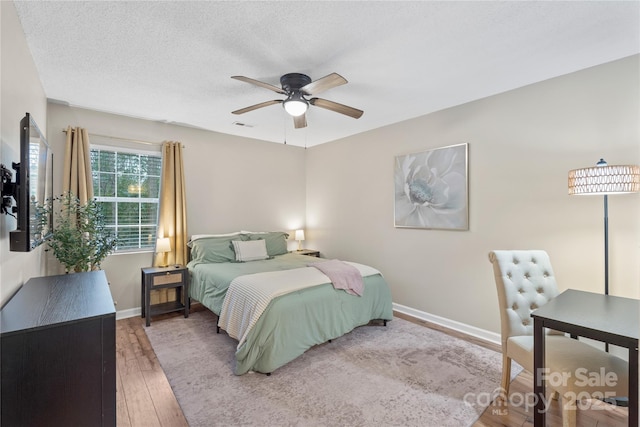 bedroom with ceiling fan, hardwood / wood-style floors, and a textured ceiling