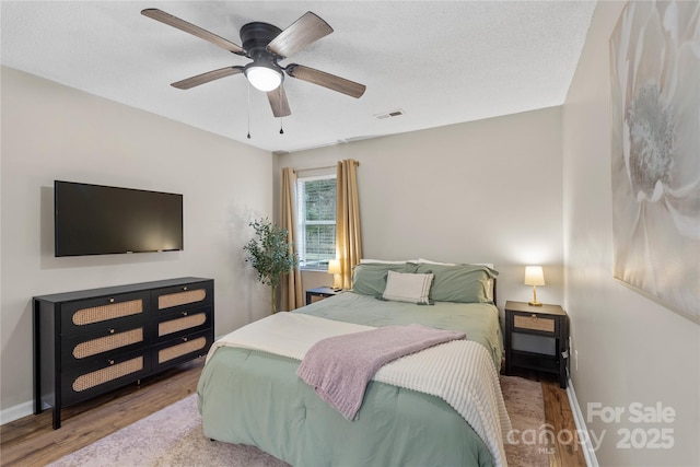 bedroom with ceiling fan, hardwood / wood-style flooring, and a textured ceiling