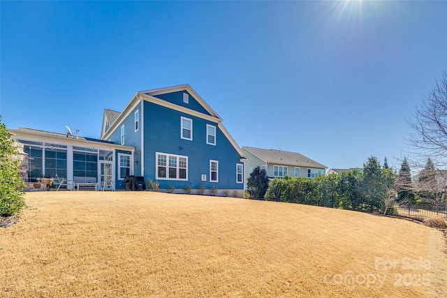 back of house featuring a lawn and a sunroom