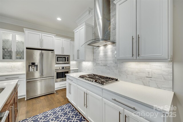 kitchen with white cabinets, crown molding, stainless steel appliances, and wall chimney exhaust hood