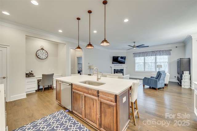 kitchen with sink, decorative light fixtures, built in desk, a center island with sink, and stainless steel dishwasher