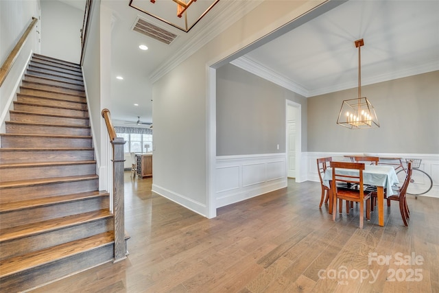 dining space with an inviting chandelier, ornamental molding, and light hardwood / wood-style floors