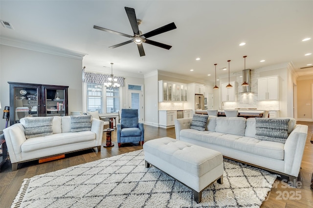 living room with ornamental molding, wood-type flooring, and ceiling fan with notable chandelier