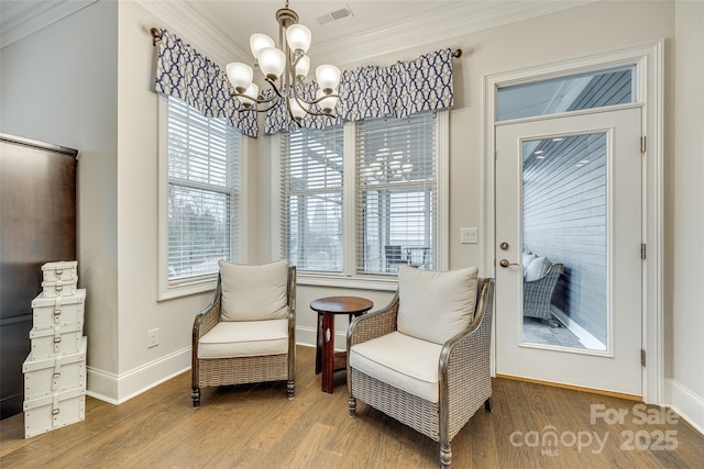 sitting room with hardwood / wood-style flooring, crown molding, and a notable chandelier