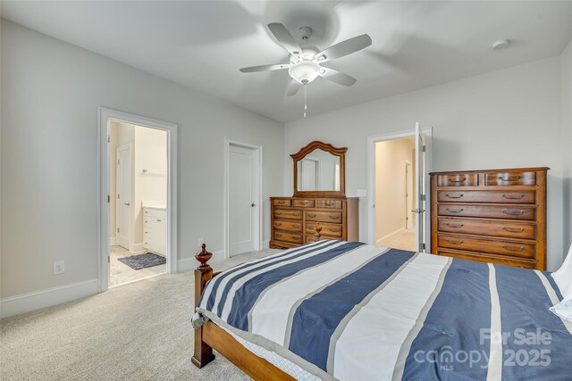 bedroom featuring ceiling fan, light colored carpet, and ensuite bath