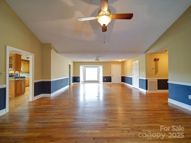 unfurnished living room with hardwood / wood-style flooring, vaulted ceiling, and ceiling fan