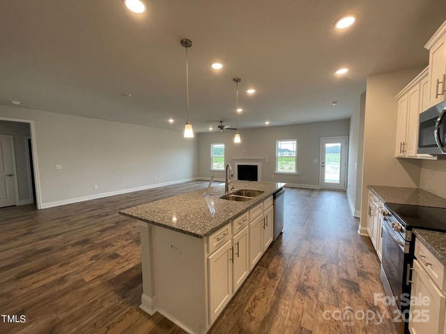 kitchen with sink, pendant lighting, stainless steel appliances, a kitchen island with sink, and white cabinets