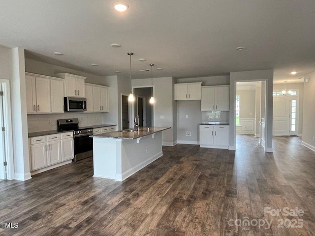 kitchen featuring stainless steel appliances, a center island with sink, white cabinets, and dark hardwood / wood-style flooring