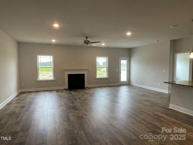 unfurnished living room with dark wood-type flooring and ceiling fan