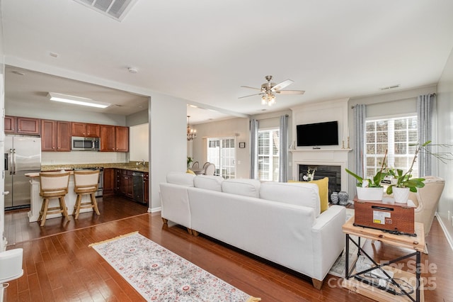 living room with dark wood-type flooring, a healthy amount of sunlight, ceiling fan with notable chandelier, and sink