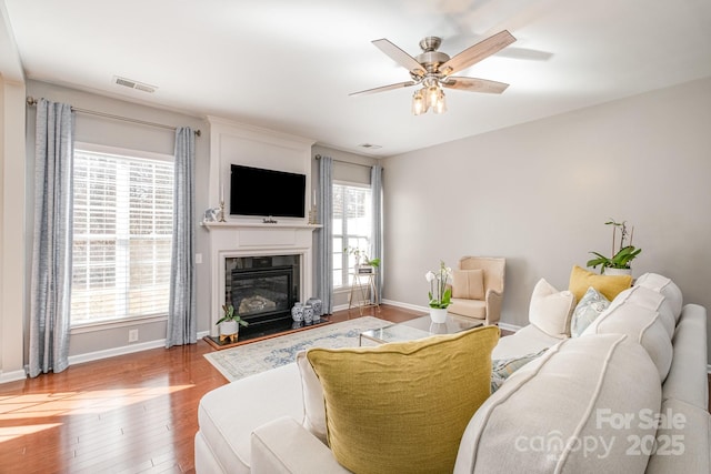 living room with hardwood / wood-style floors, a high end fireplace, and ceiling fan