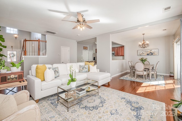 living room featuring ceiling fan with notable chandelier and light wood-type flooring